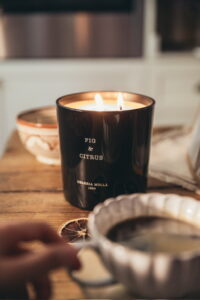 Persona tomando un té con una vela encendida, representando una pausa consciente y el concepto de comprar con calma.