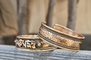 Persona colocando una pulsera de cobre en la mano izquierda, mostrando cómo usarla correctamente según sus beneficios.